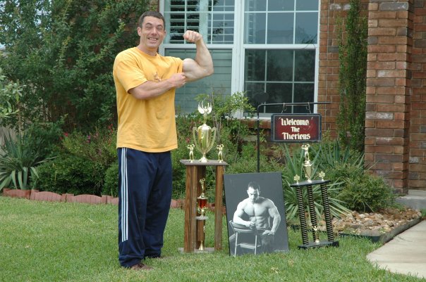 Joel Therien posing with his body building trophies